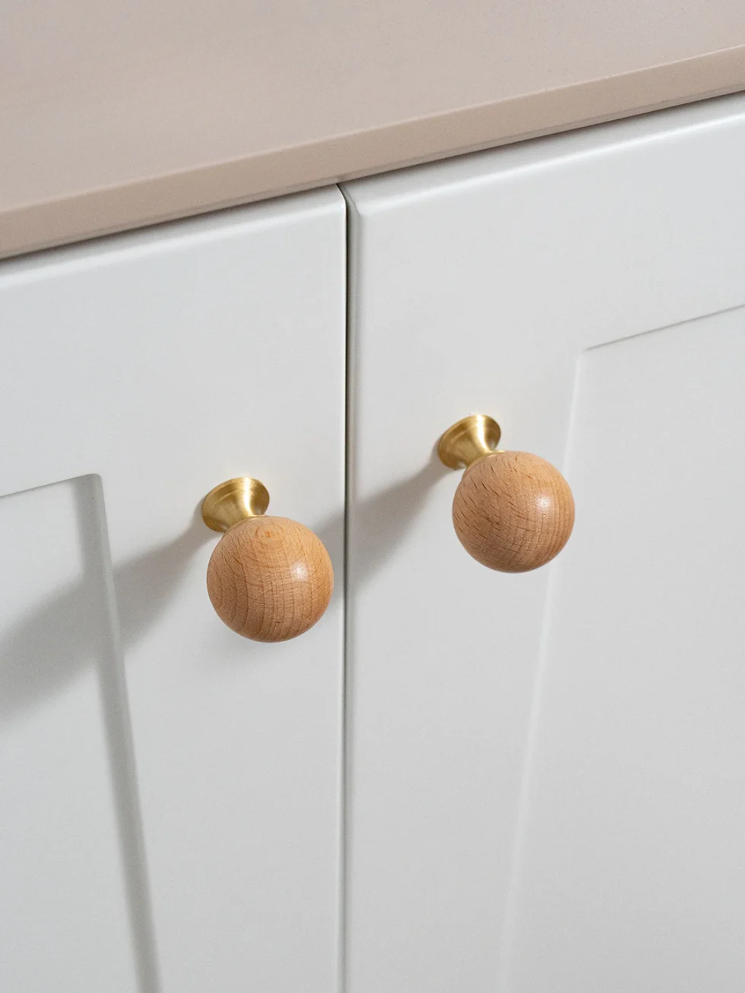 Close-up of white cabinets with wooden knobs on a neutral background