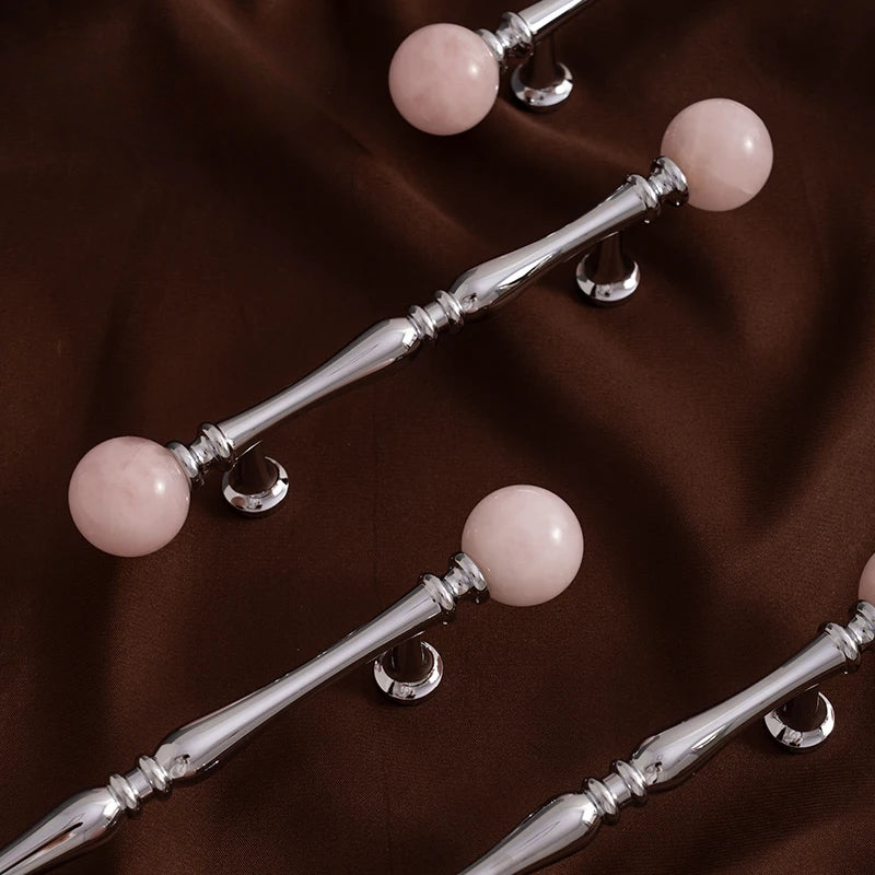 Silver handles with pink spherical ends on a brown fabric background