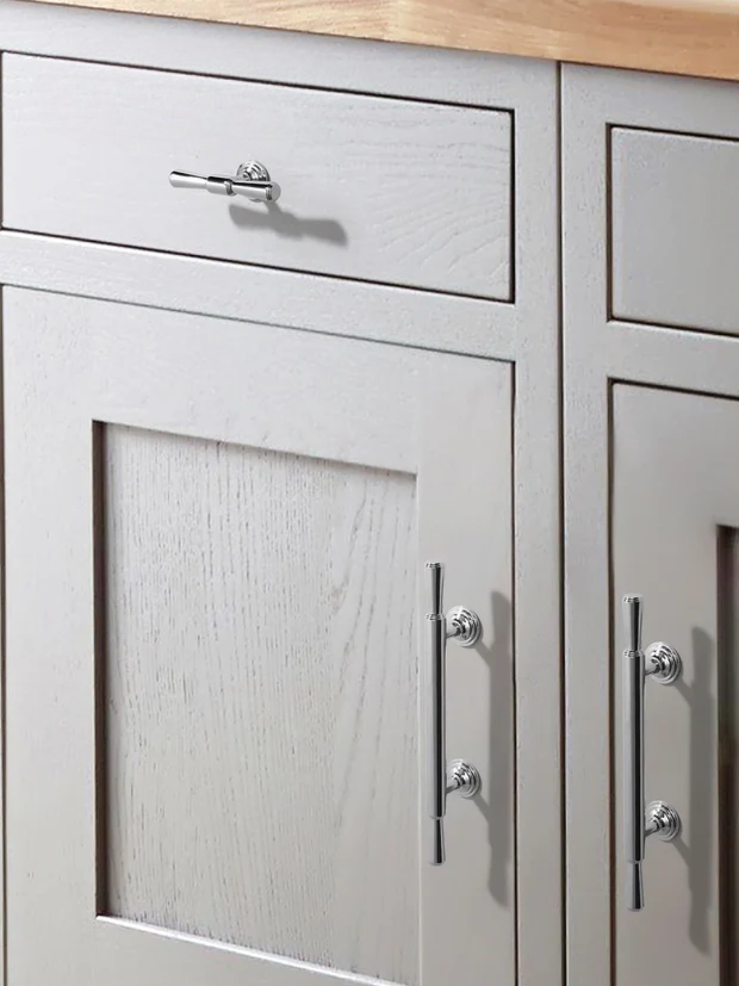 Gray kitchen cabinets with silver handles and a wooden countertop.