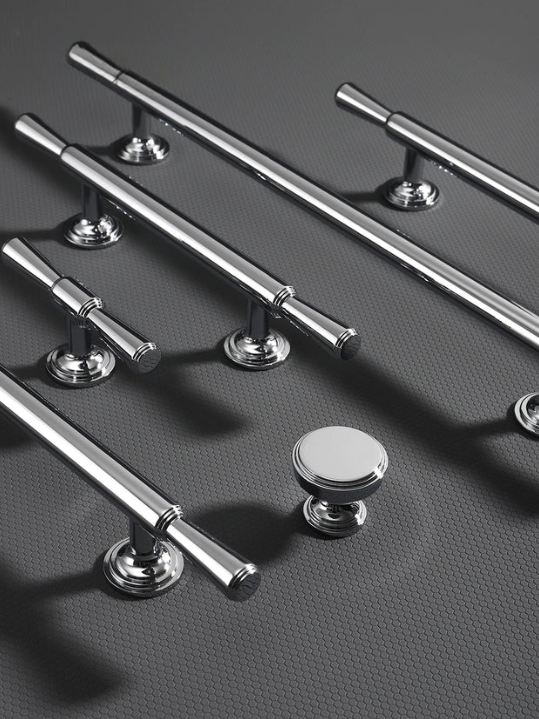 Set of metallic door handles and knobs on a textured gray surface