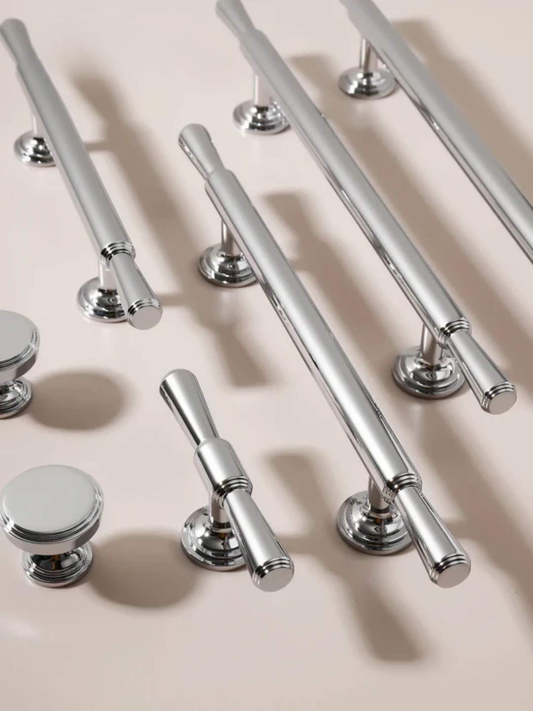 Collection of silver cabinet handles and knobs on a beige background