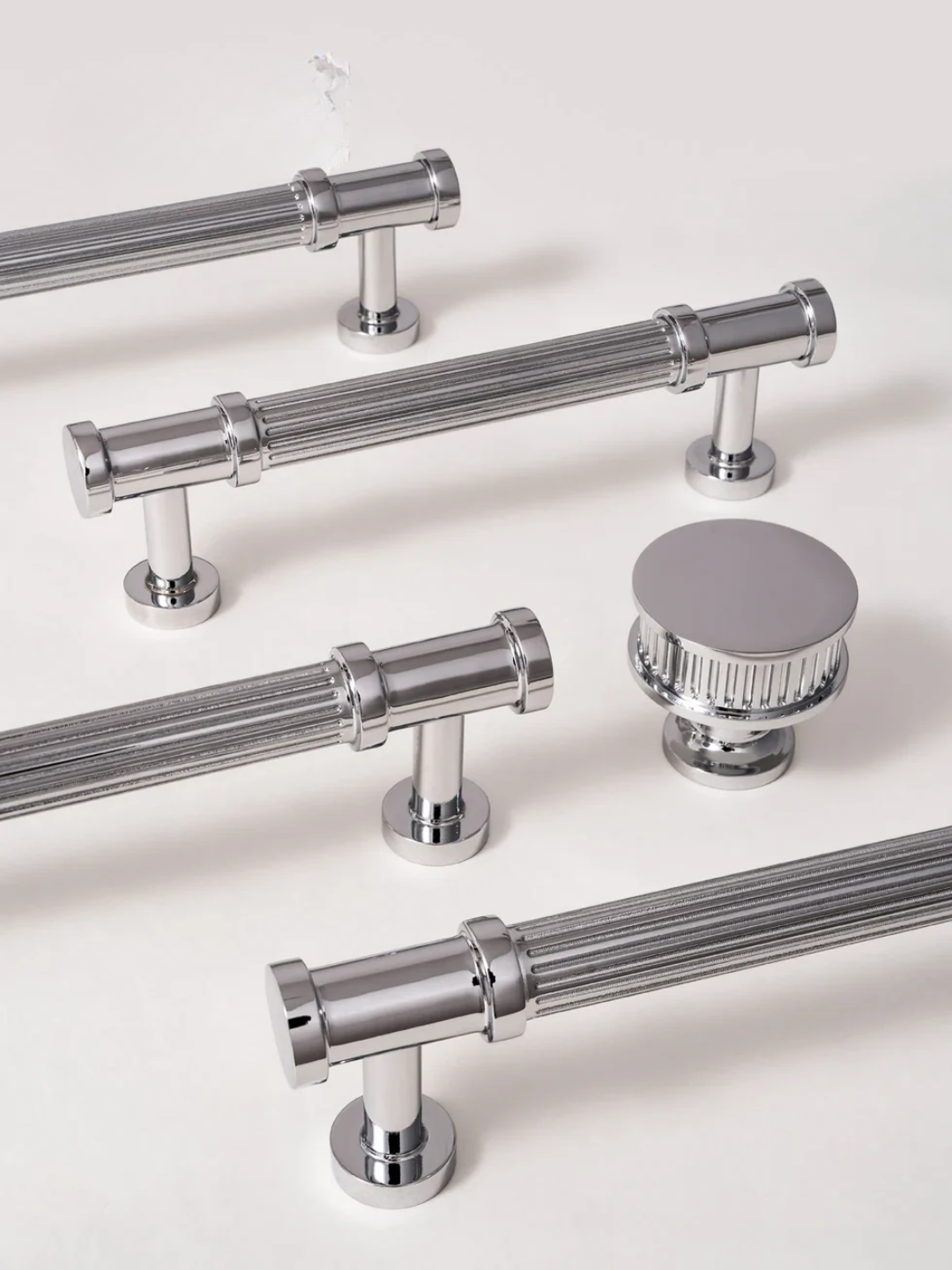 Set of chrome cabinet handles and knobs on a white background