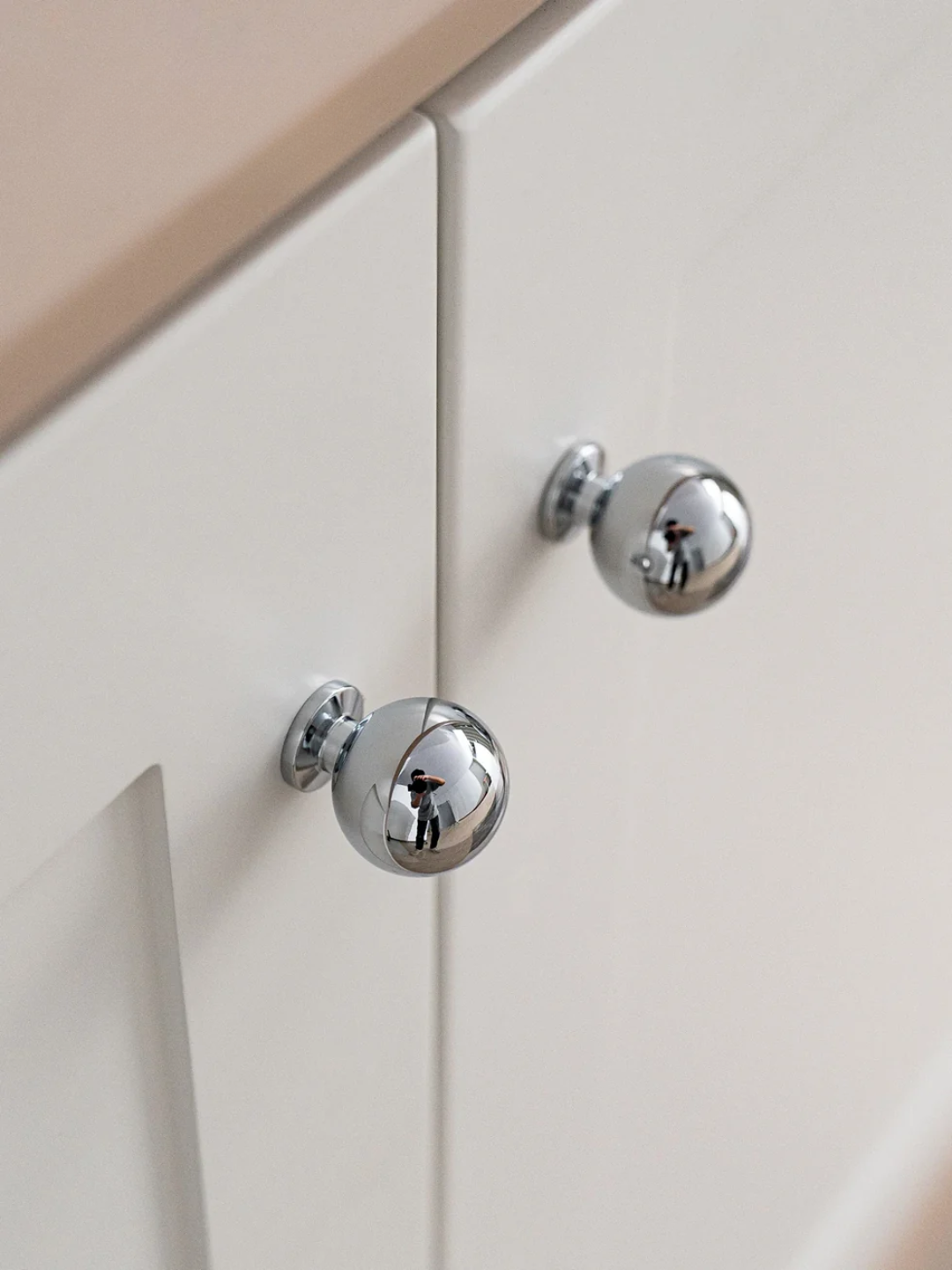 Close-up of a cabinet with chrome knobs on a light-colored background