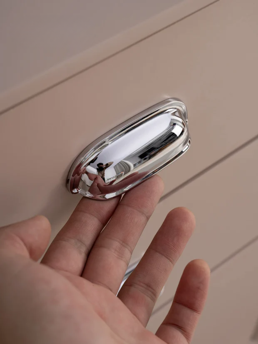 Metallic handle held in a hand against a neutral background