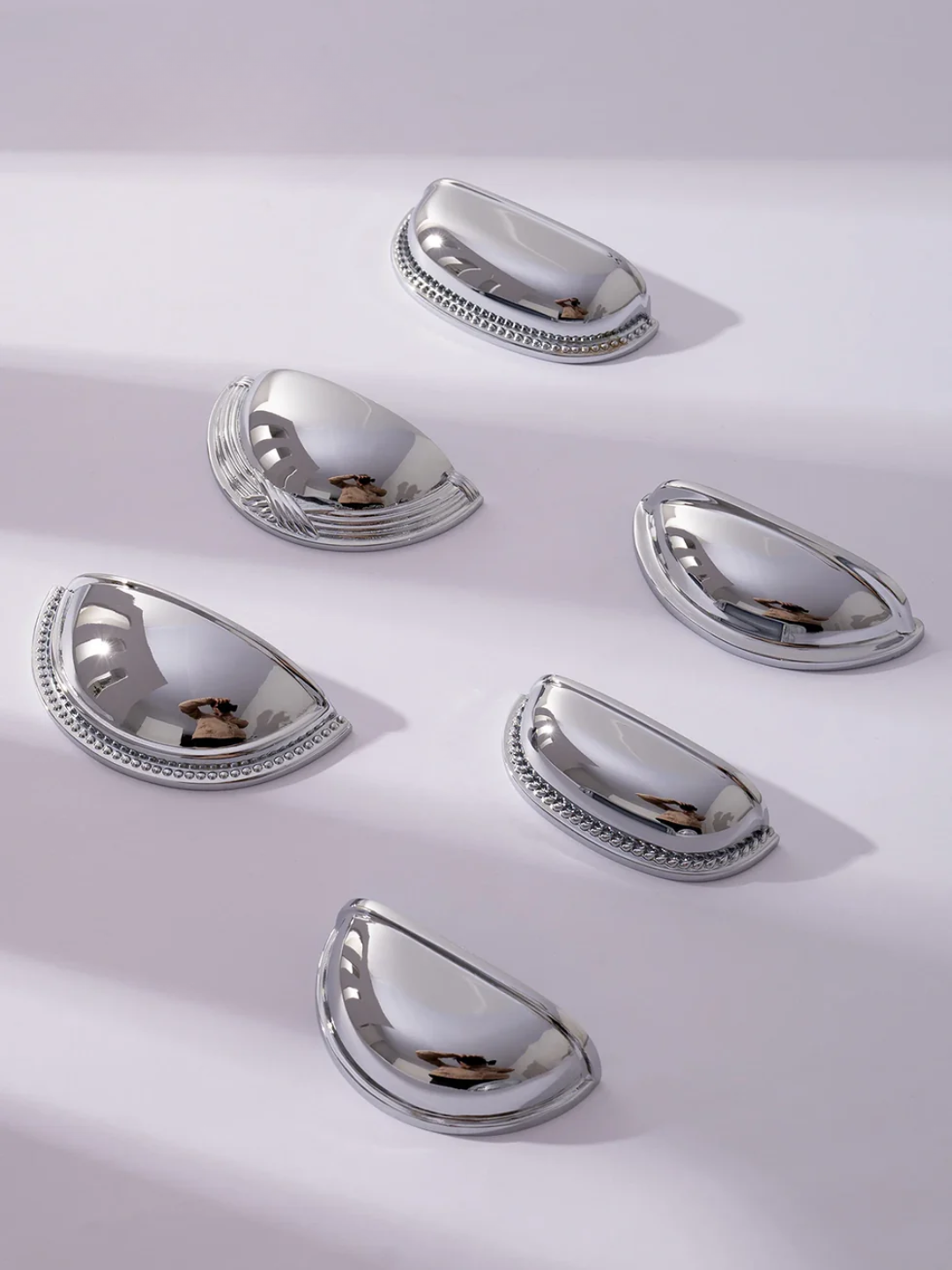Set of silver teardrop-shaped objects on a light gray background