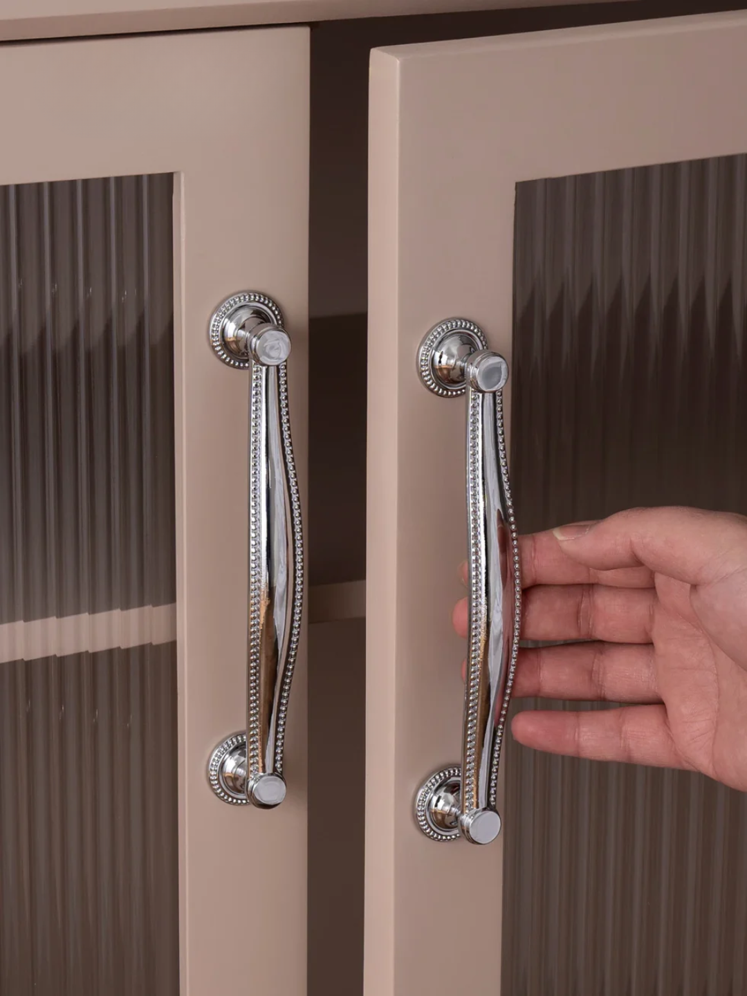 Hand opening a cabinet door with decorative handles