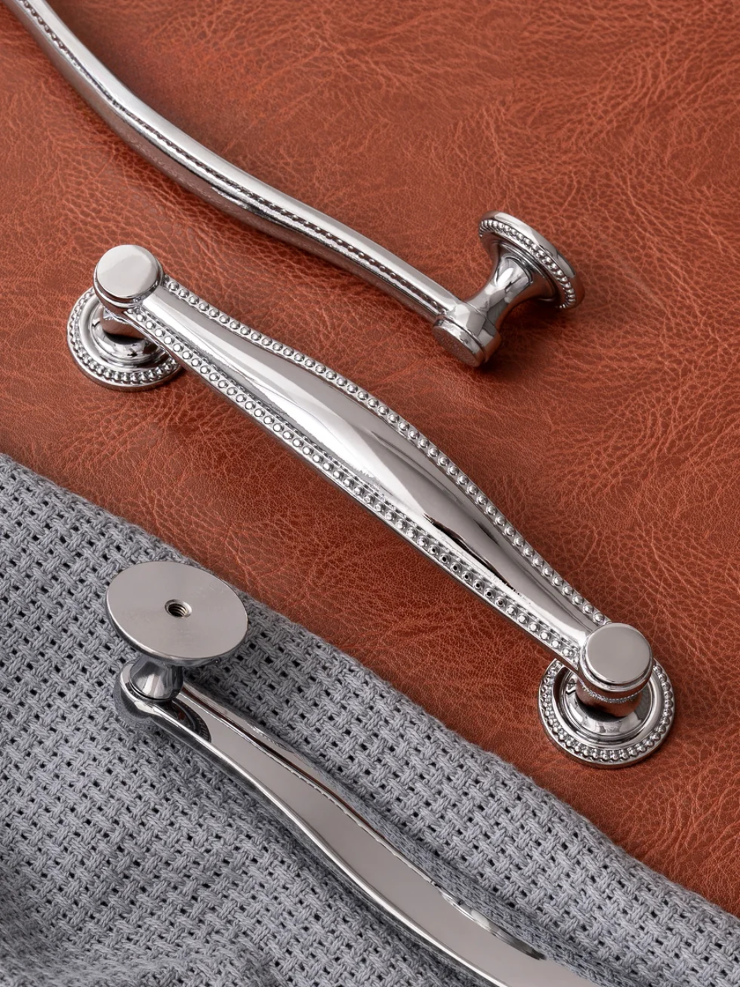 Close-up of silver handles on a brown leather bag with a gray interior.