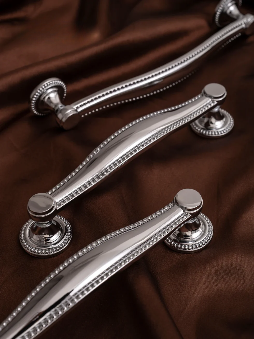 Close-up of three silver handles on a brown fabric background