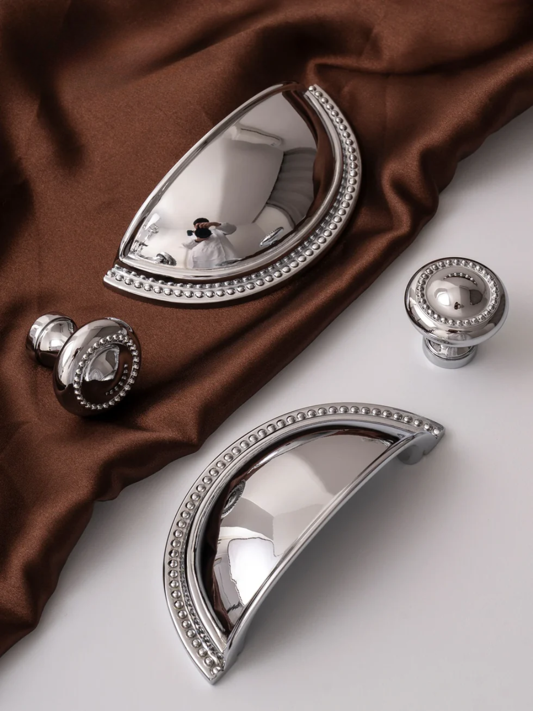 Decorative silver door handles on a brown fabric background