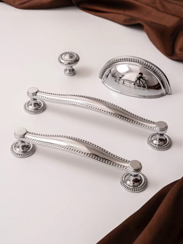 Silver cabinet handles and knobs on a white surface.