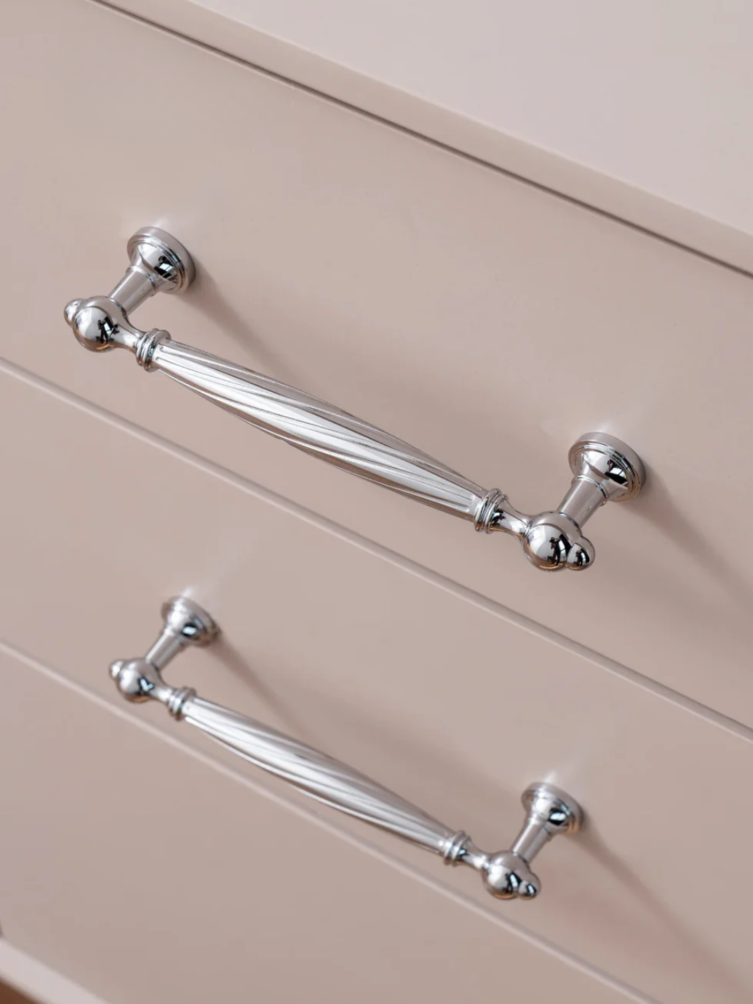 Close-up of metallic cabinet handles on a beige cabinet