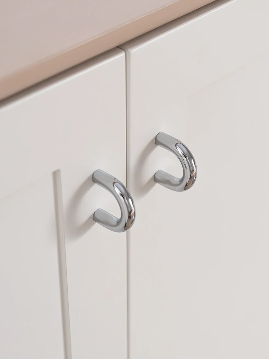 Close-up of metallic cabinet handles on a white cabinet door.
