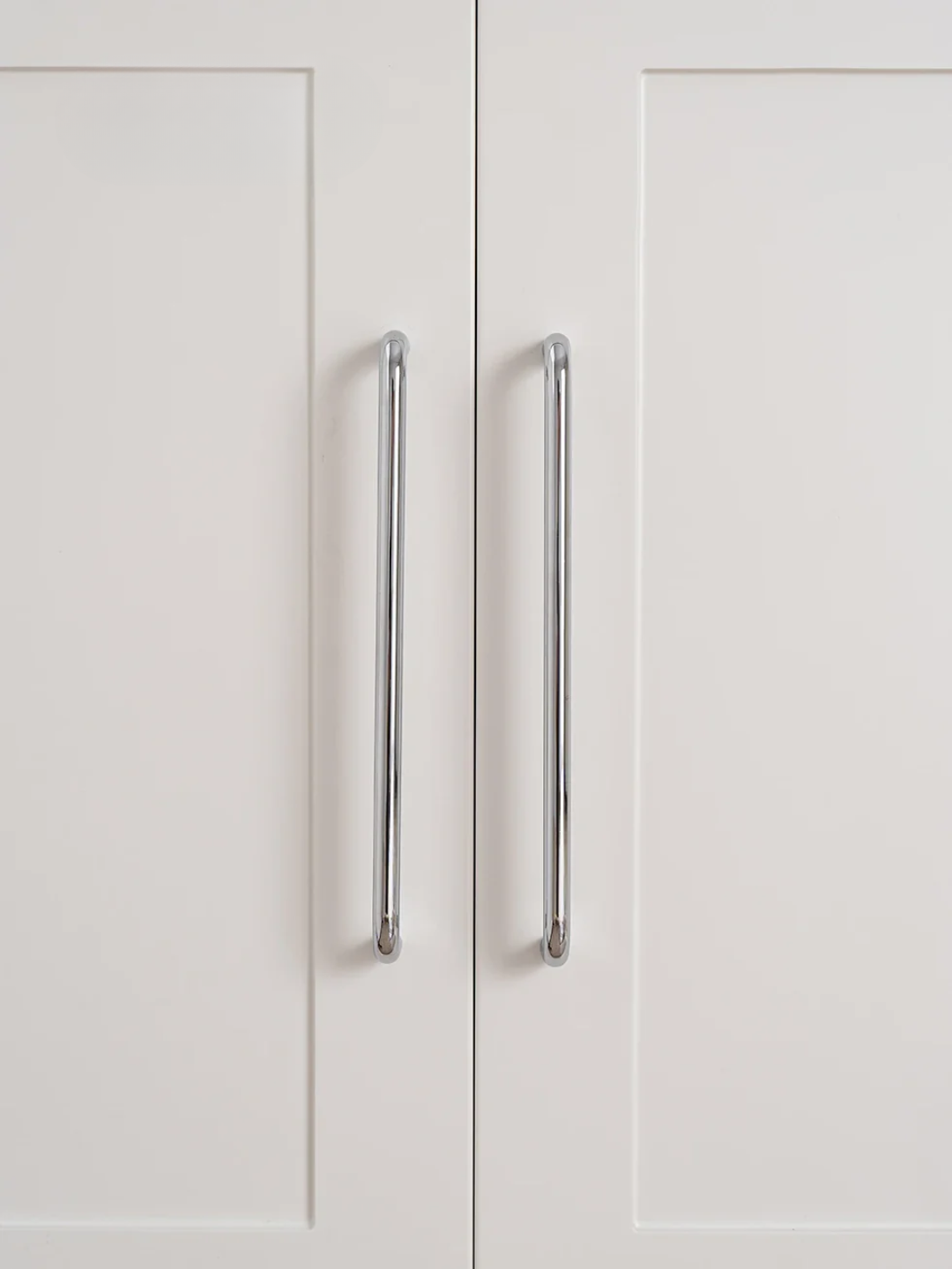Close-up of a white cabinet with silver handles on a light gray background