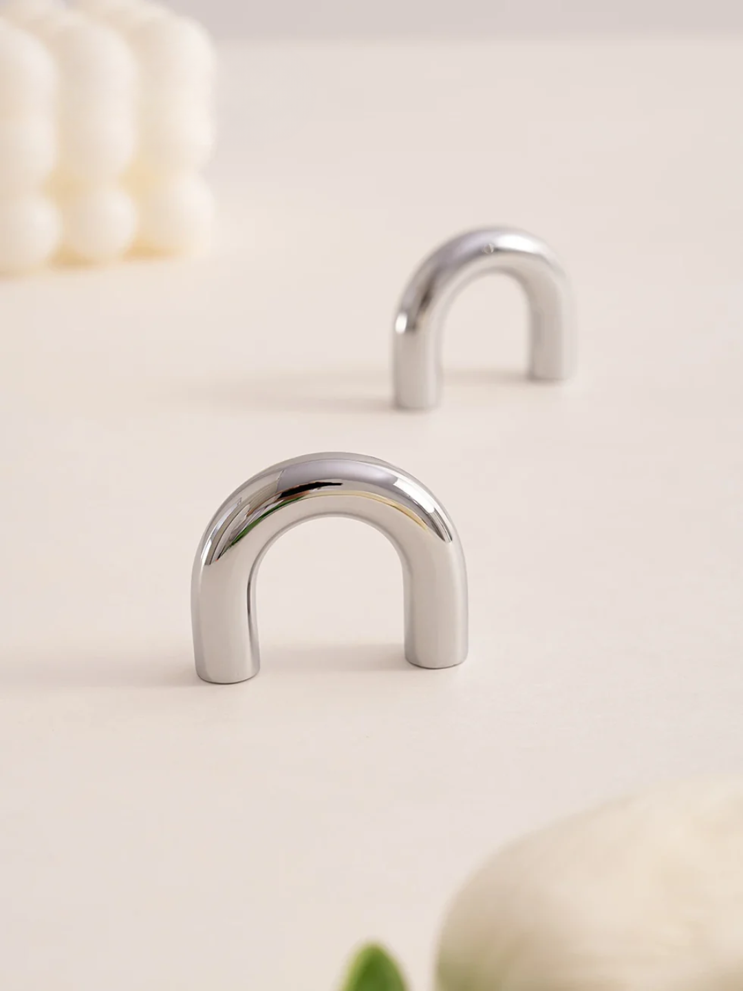 Two silver U-shaped objects on a light beige background