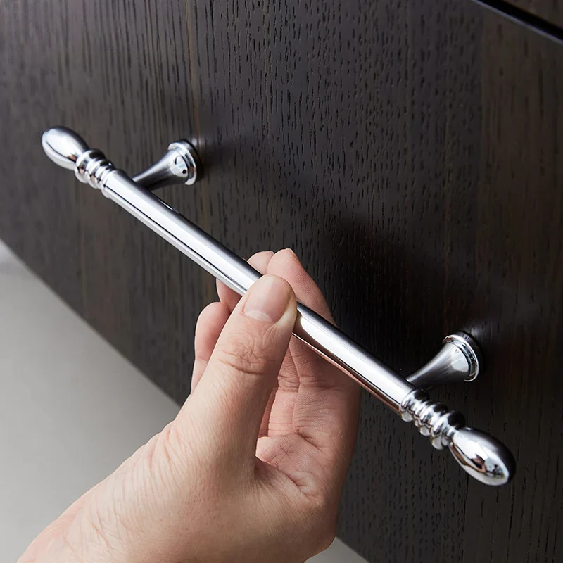 Hand holding a silver curtain rod against a wooden background