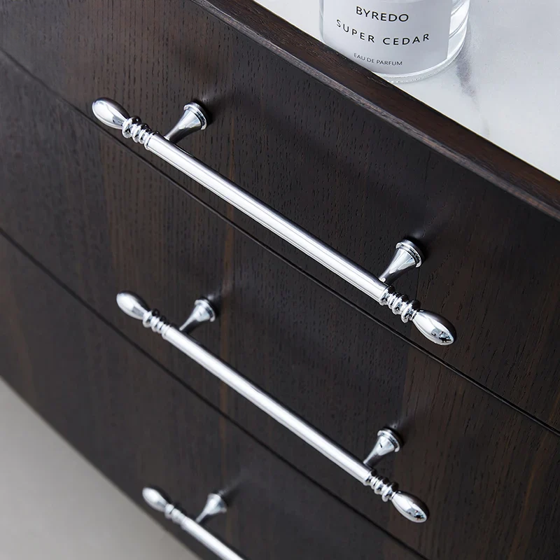 Dark wooden dresser with silver handles and a Byredo perfume bottle in the background.
