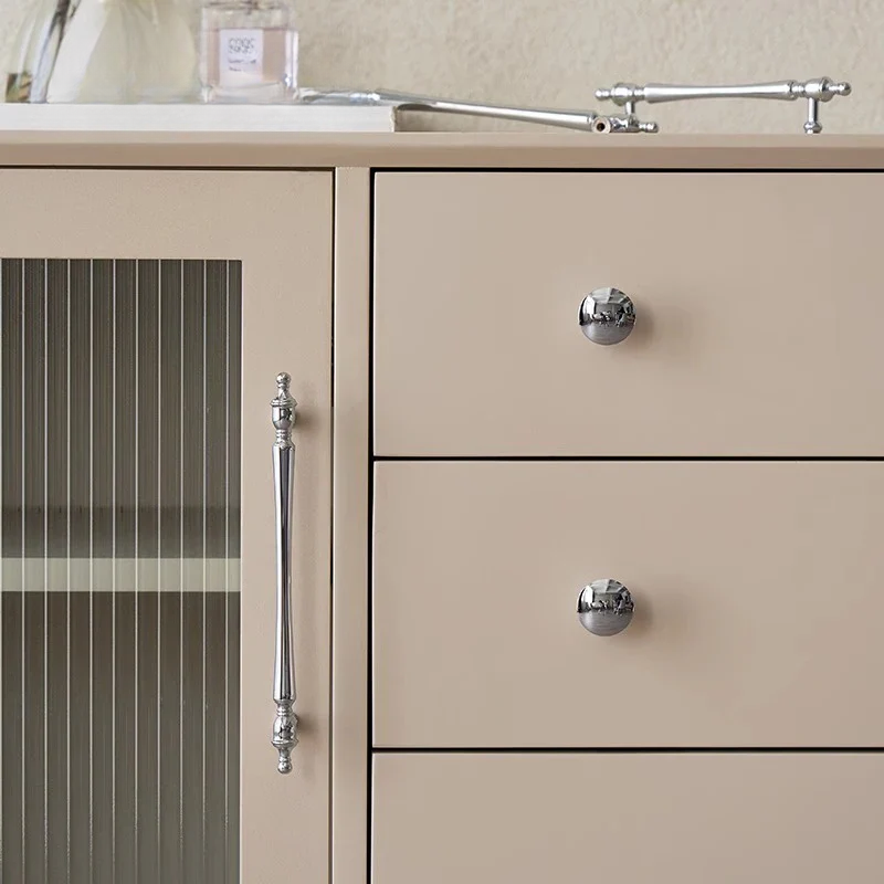 Beige kitchen cabinet with silver handles and a glass-fronted drawer.