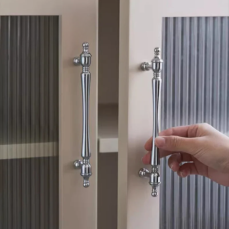 Hand opening a door with decorative silver handles.