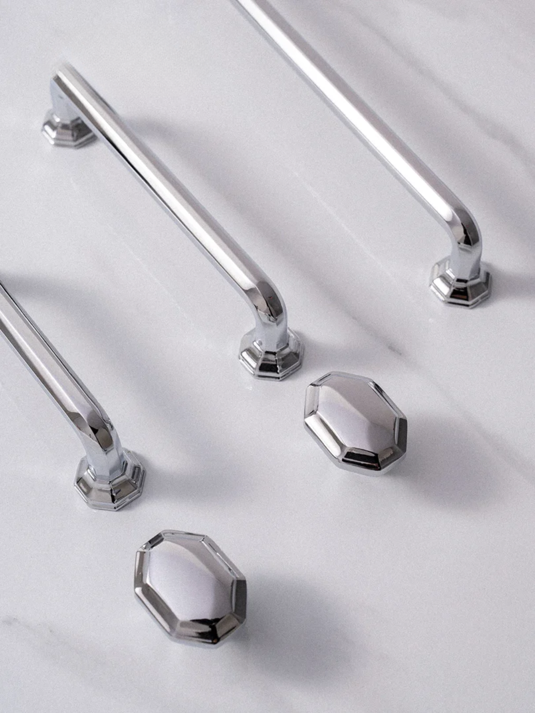 Chrome cabinet handles and knobs on a light gray background