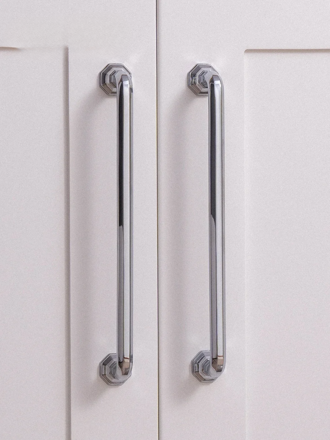 Close-up of a white cabinet with chrome handles on a white background