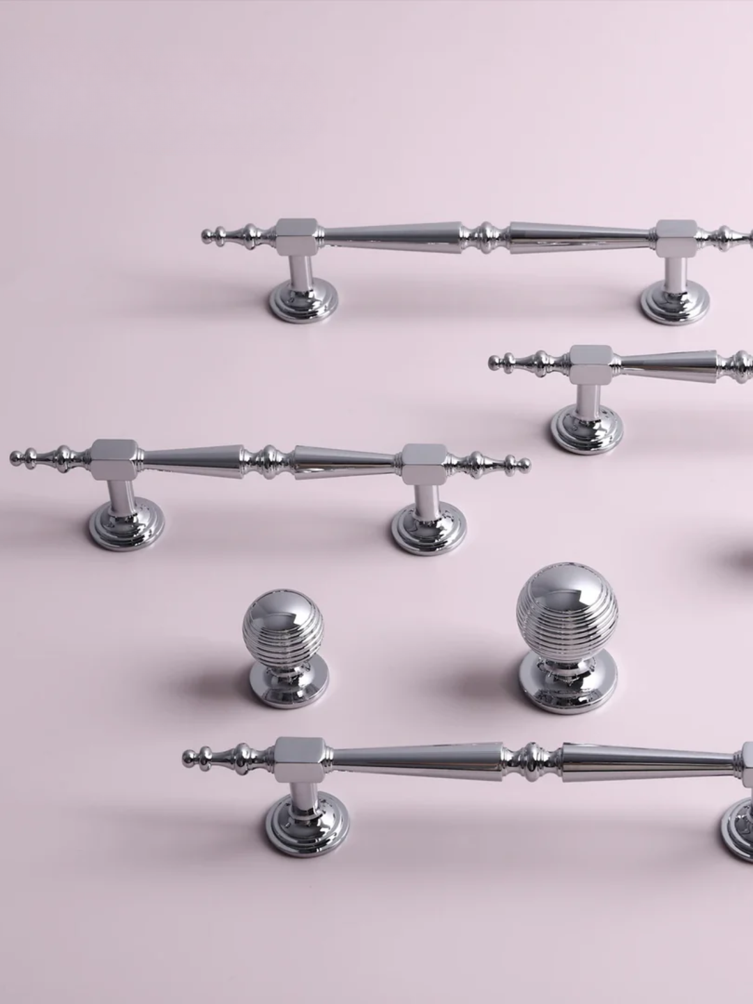 Collection of silver cabinet handles and knobs on a pink background