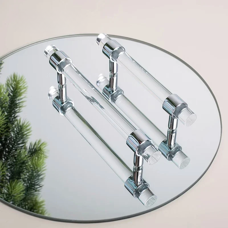 Chrome towel rack on a round glass mirror with a blurred green plant in the background