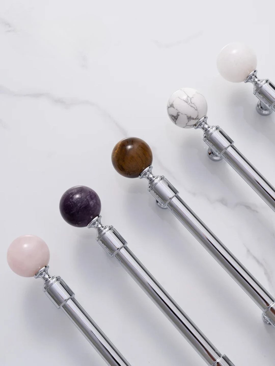 Decorative curtain rods with colorful spherical finials on a marble surface