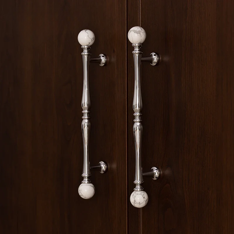 Silver cabinet handles with marble knobs on a wooden door