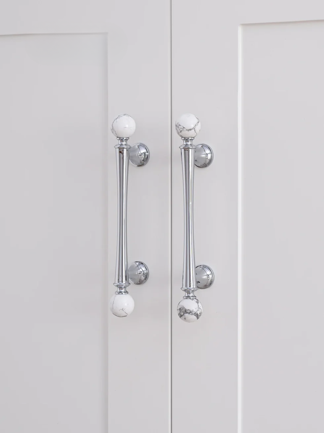 Close-up of silver cabinet handles on a white door