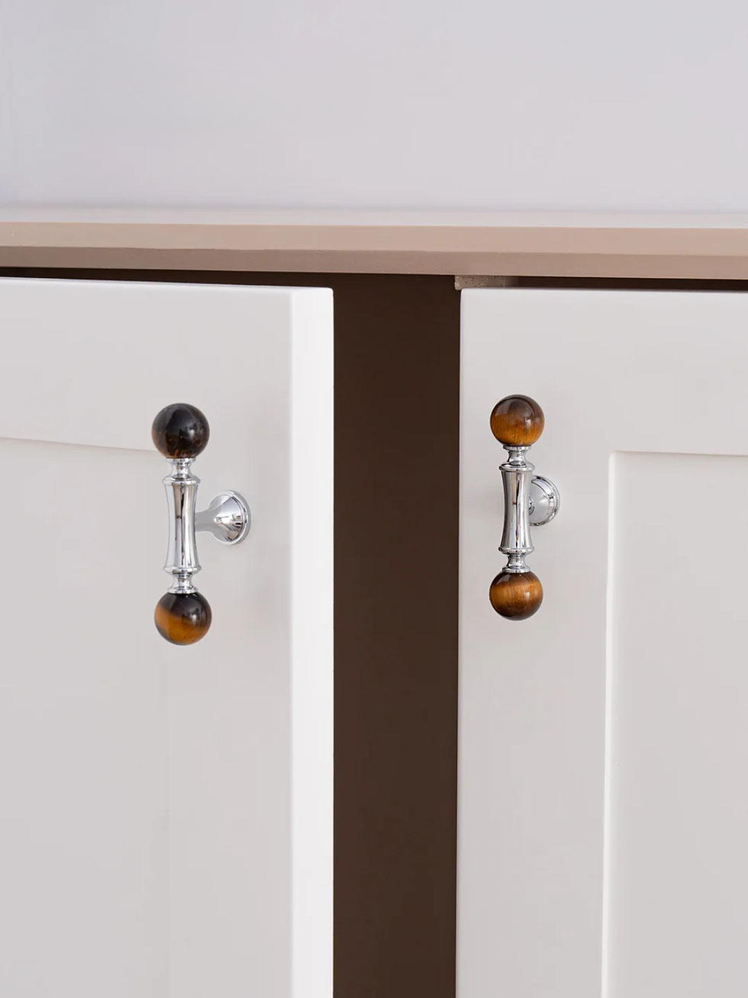 Close-up of cabinet doors with decorative handles on a neutral background