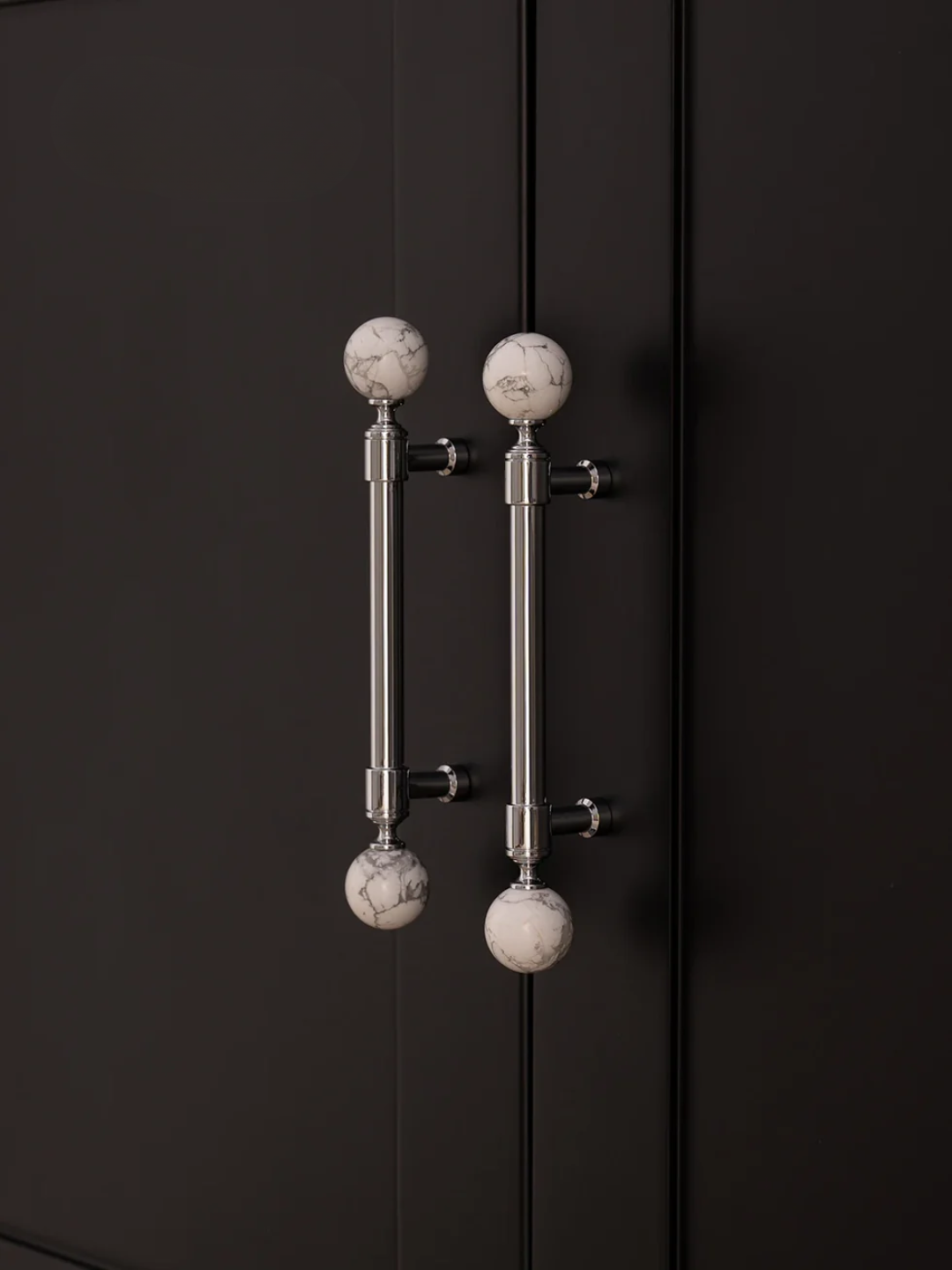 Decorative wall-mounted fixture with marble-like spherical ends on a black background