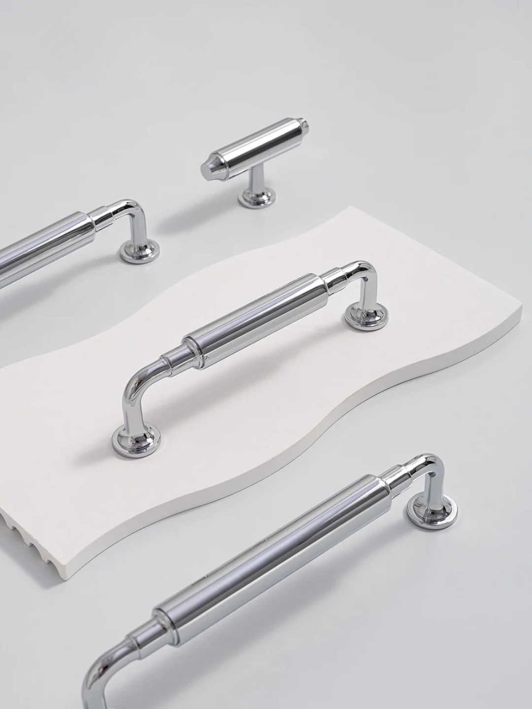 Set of chrome cabinet handles on a white surface