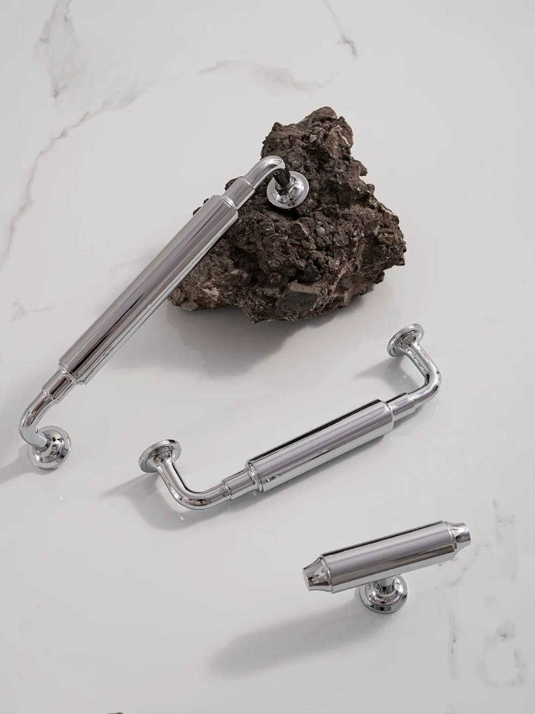 Set of chrome cabinet handles on a white surface