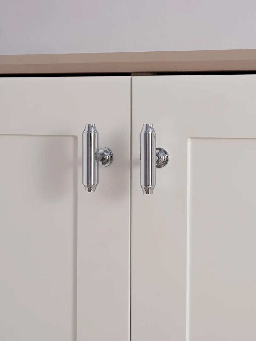 Close-up of a cabinet with chrome handles on a white background