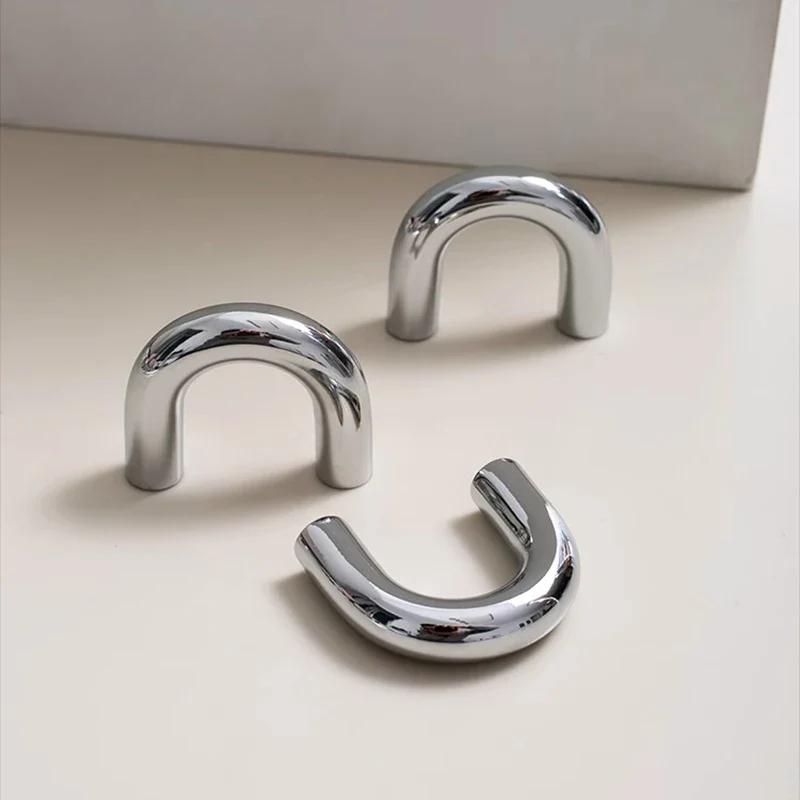 Three chrome U-shaped handles on a light beige surface with a neutral background