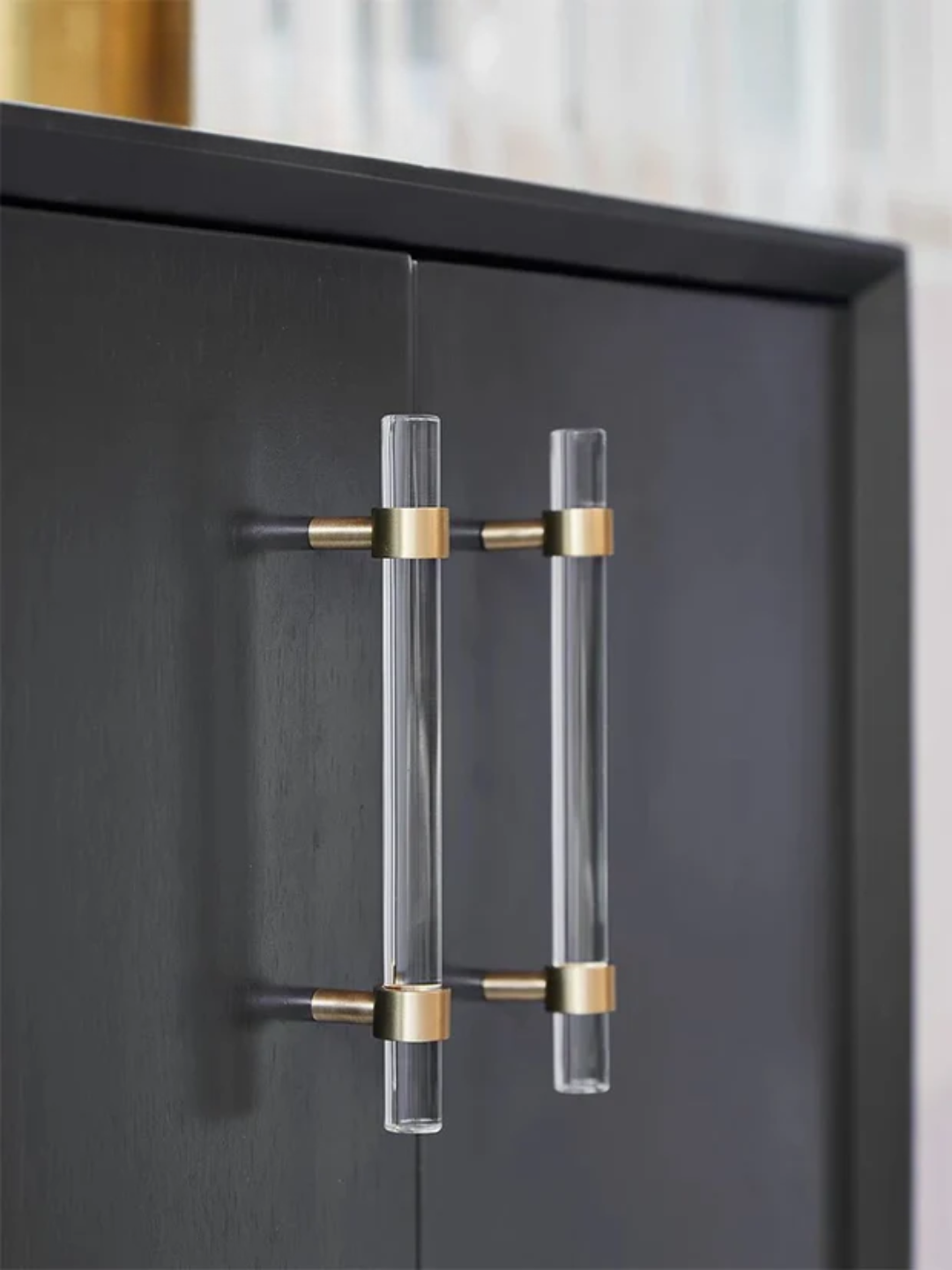Clear acrylic handles with gold accents on a black cabinet.