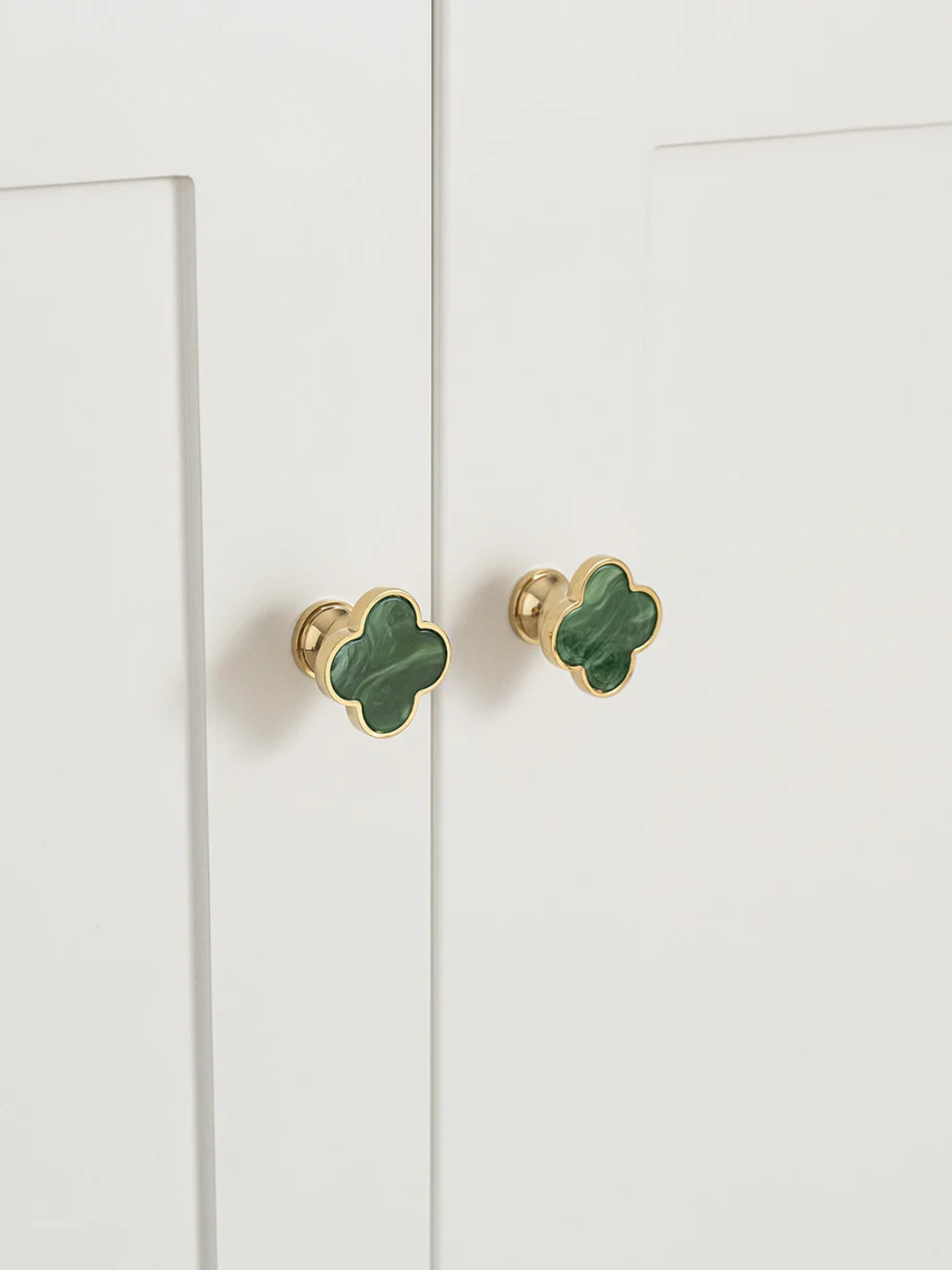 Green clover-shaped cabinet knobs on a white cabinet.