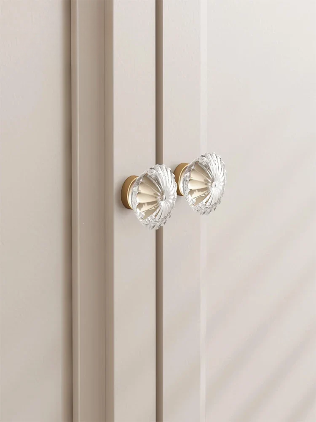 Close-up of a beige cabinet with crystal glass knobs on a neutral background