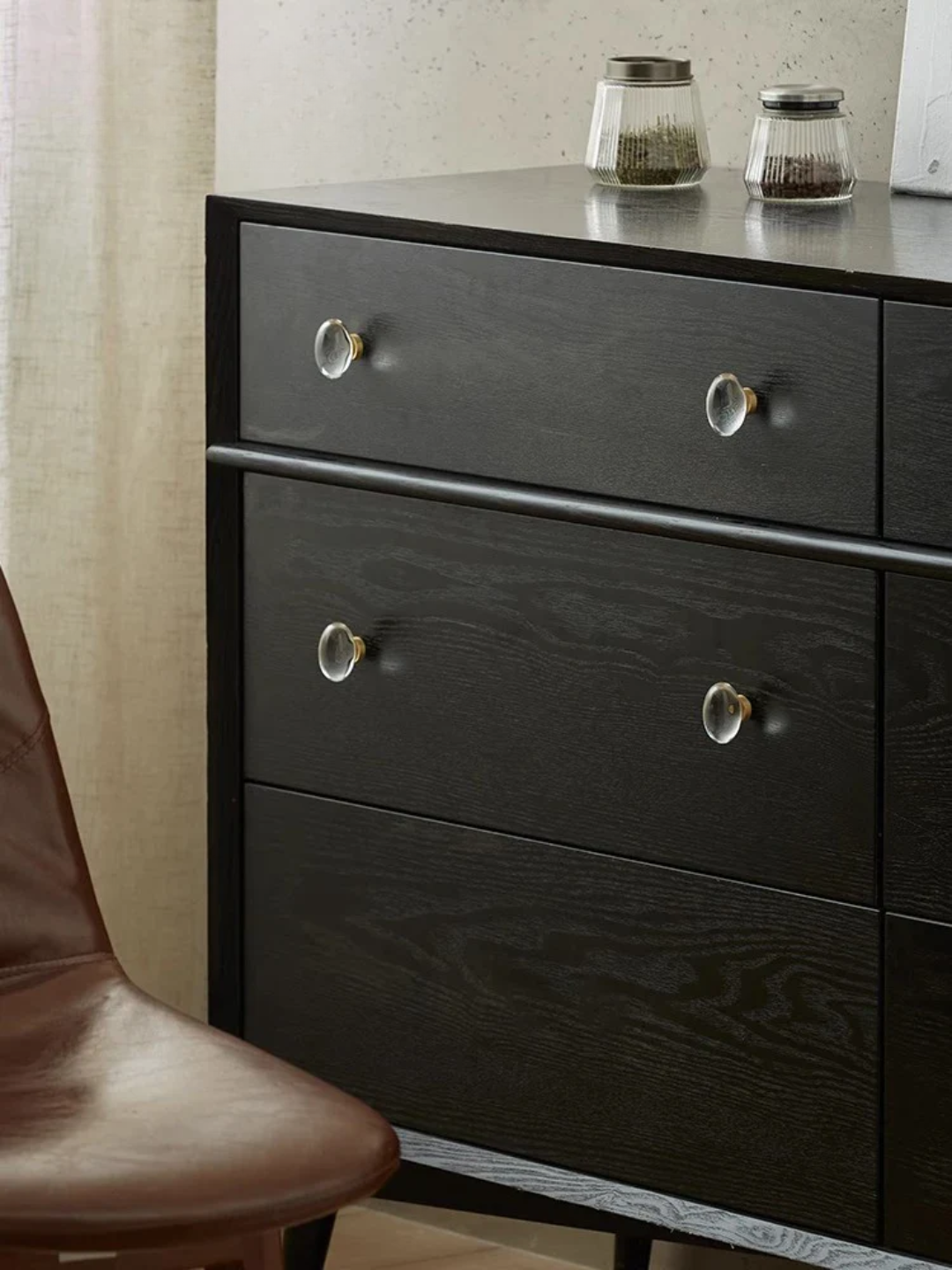 Dark wooden dresser with glass knobs in a room setting