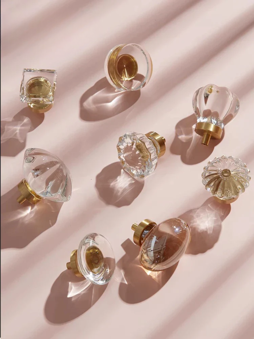 Clear glass door knobs with gold accents on a pink background