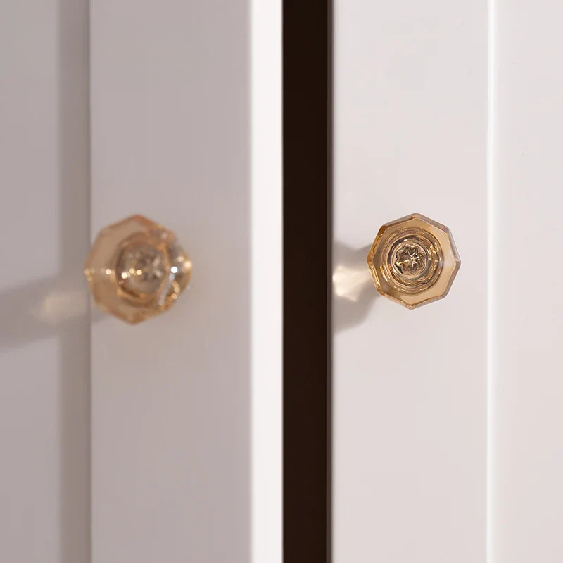 Close-up of a white cabinet with gold knobs on a neutral background