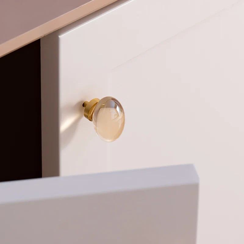 Close-up of a gold cabinet knob on a white drawer