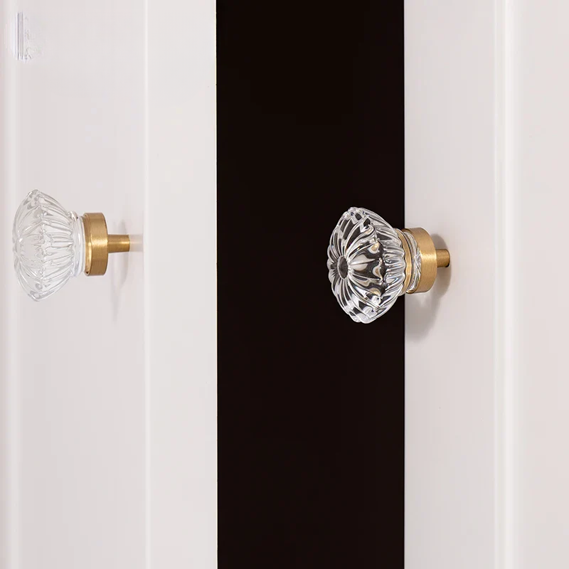 Glass door knobs on a white cabinet with a black stripe.