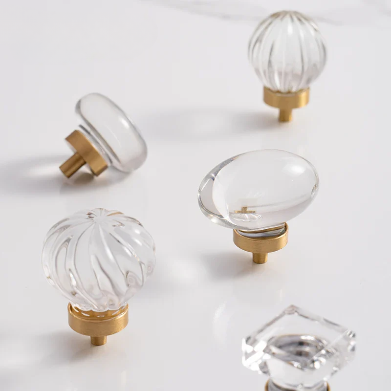 Clear glass door knobs with gold bases on a light gray background