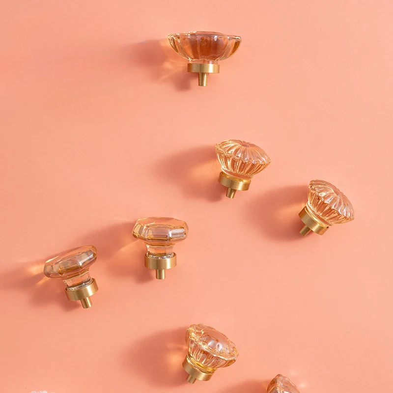 Clear glass knobs with gold bases on a pink background