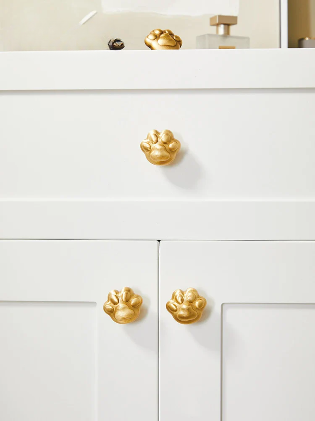 White cabinet with gold paw-shaped knobs in a bathroom setting