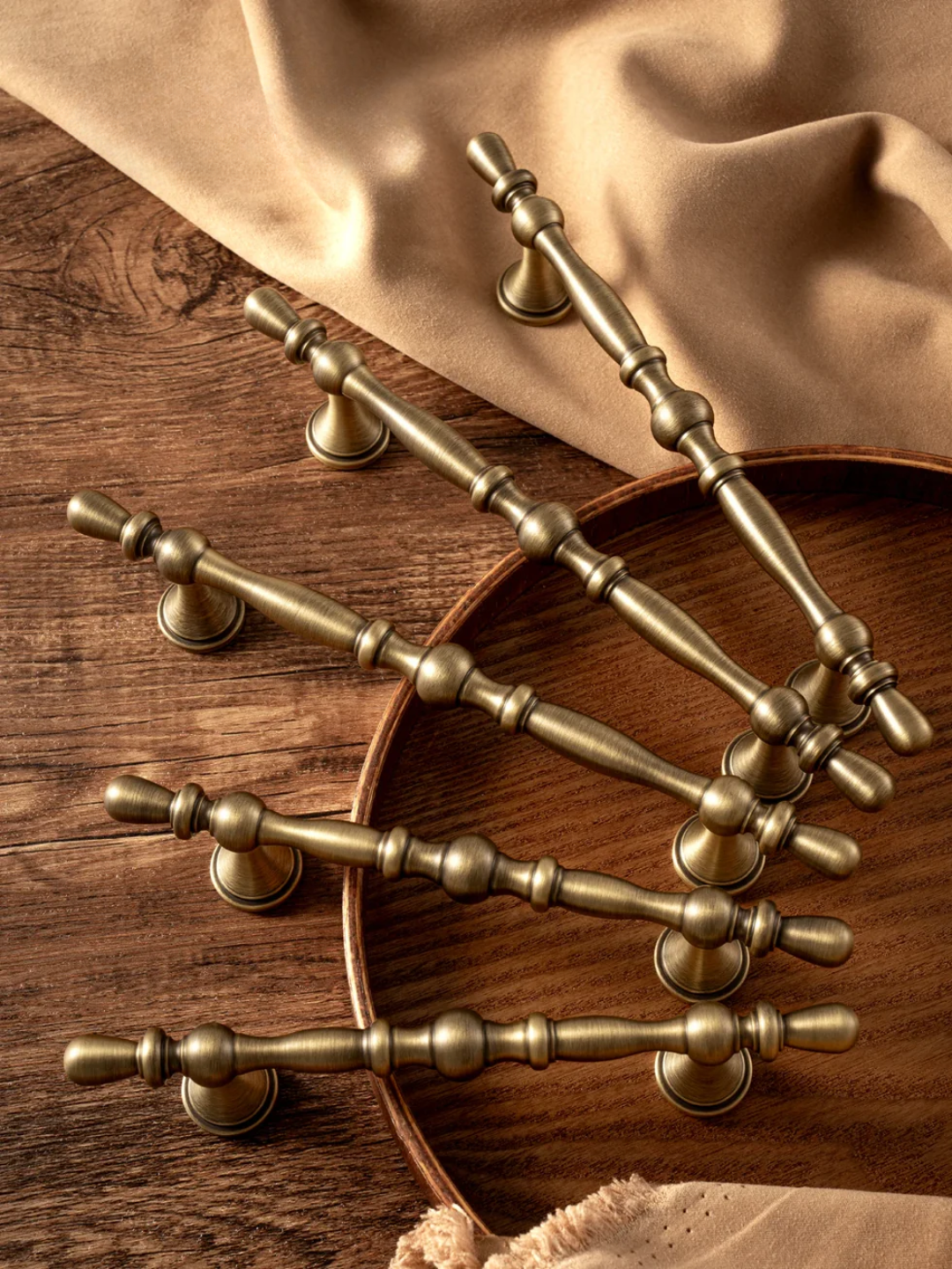 Set of brass cabinet handles on a wooden surface with fabric background
