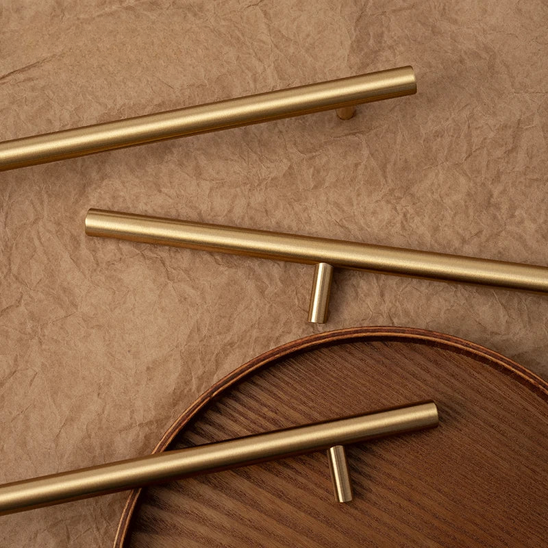 Gold cabinet handles on a wooden surface with a brown background