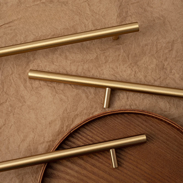 Gold cabinet handles on a wooden surface with a brown background