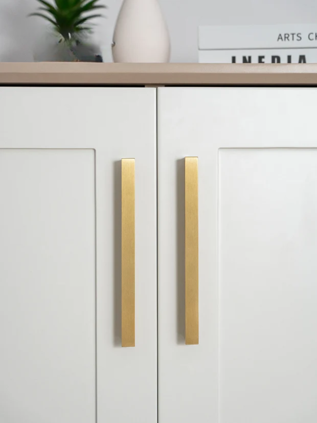 White cabinet with gold handles in a minimalistic setting